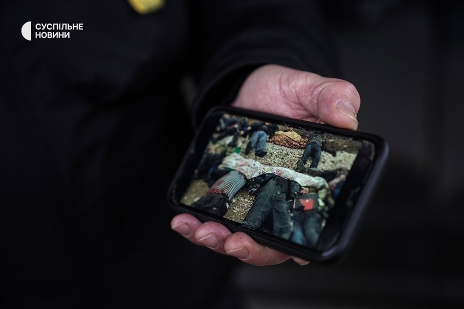 Херсонський священник Сергій Чудинович демонструє фото з поховання Героїв Бузкового парку