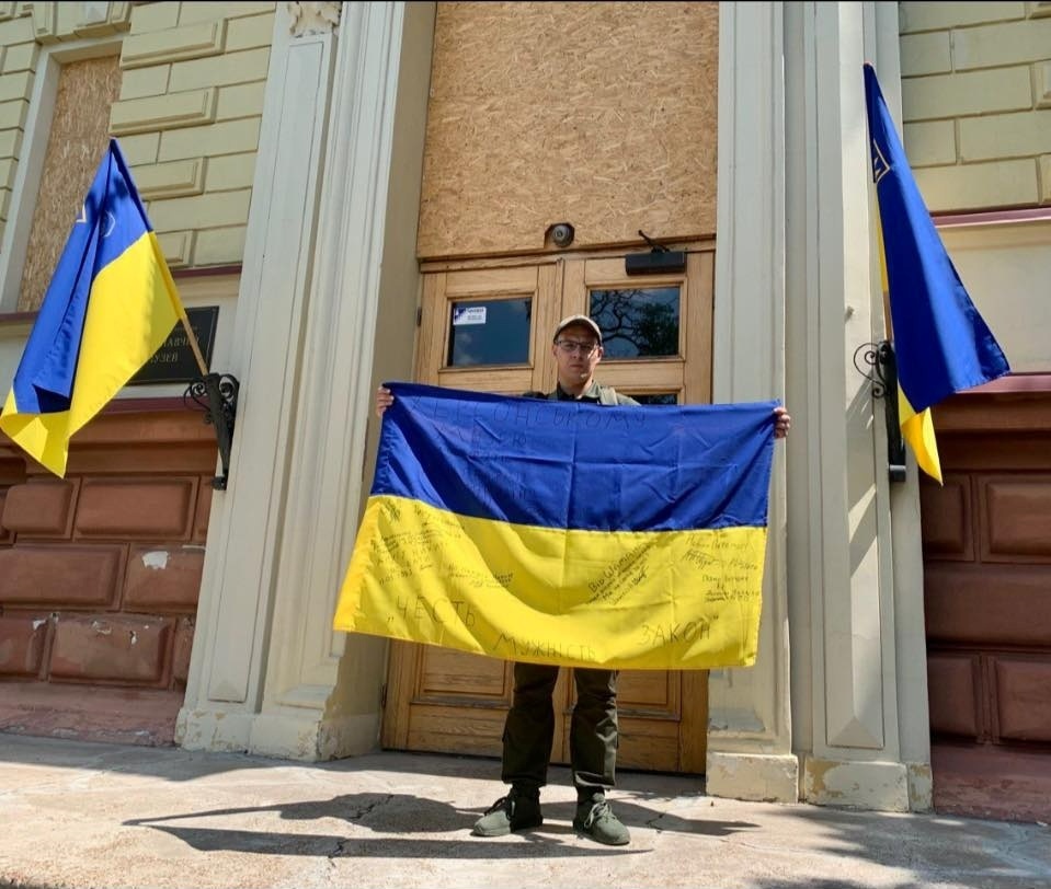 Нікіта Берчак з українським стягом, який підписали українці оборонці