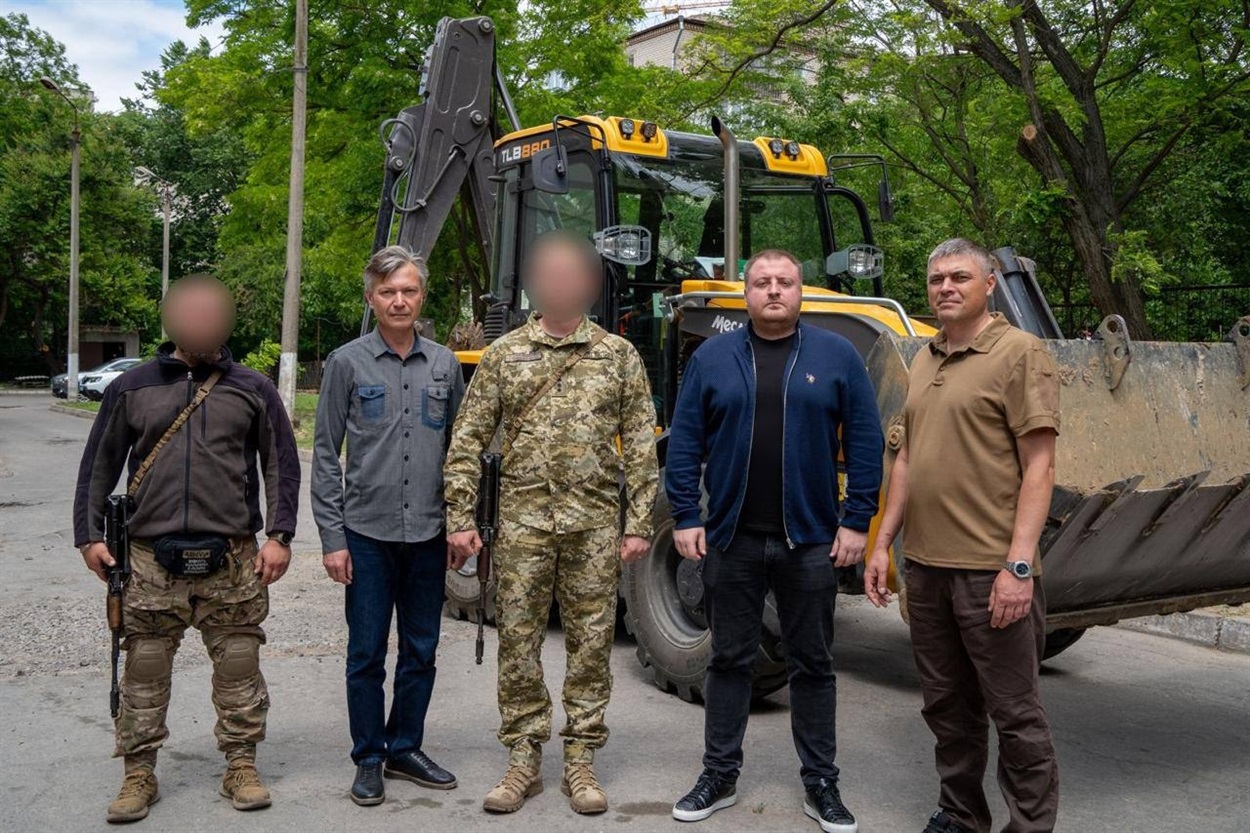 Роман Мрочко (другий праворуч) разом із військовими передають екскаватор-навантажувач