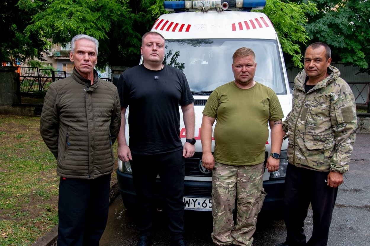 Роман Мрочко (другий ліворуч) разом із військовими передає автомобіль швидкої