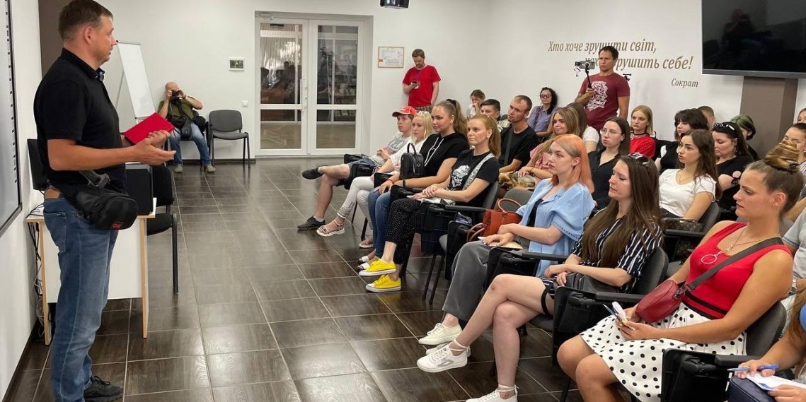 Зрадник Кирило Стремоусов виступає на організованій Алєксандром Малькєвічев «Медіашколі» у Херсоні. В кадрі видно іншого зрадника-пропагандиста Сергія Мороза (на задньому плані в багряній футболці веде зйомку дійства)
